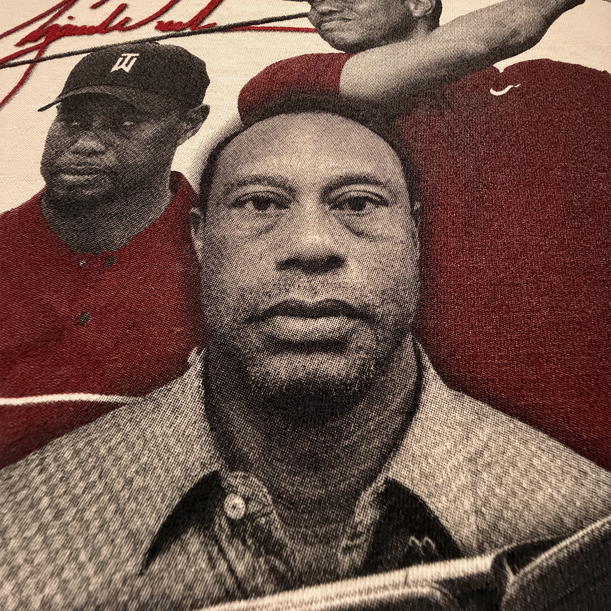 Close-up of a screen printed tshirt with a portrait of a tiger's mugshot after his range rover dui crash in the foreground and two other pictures of woods in the background.