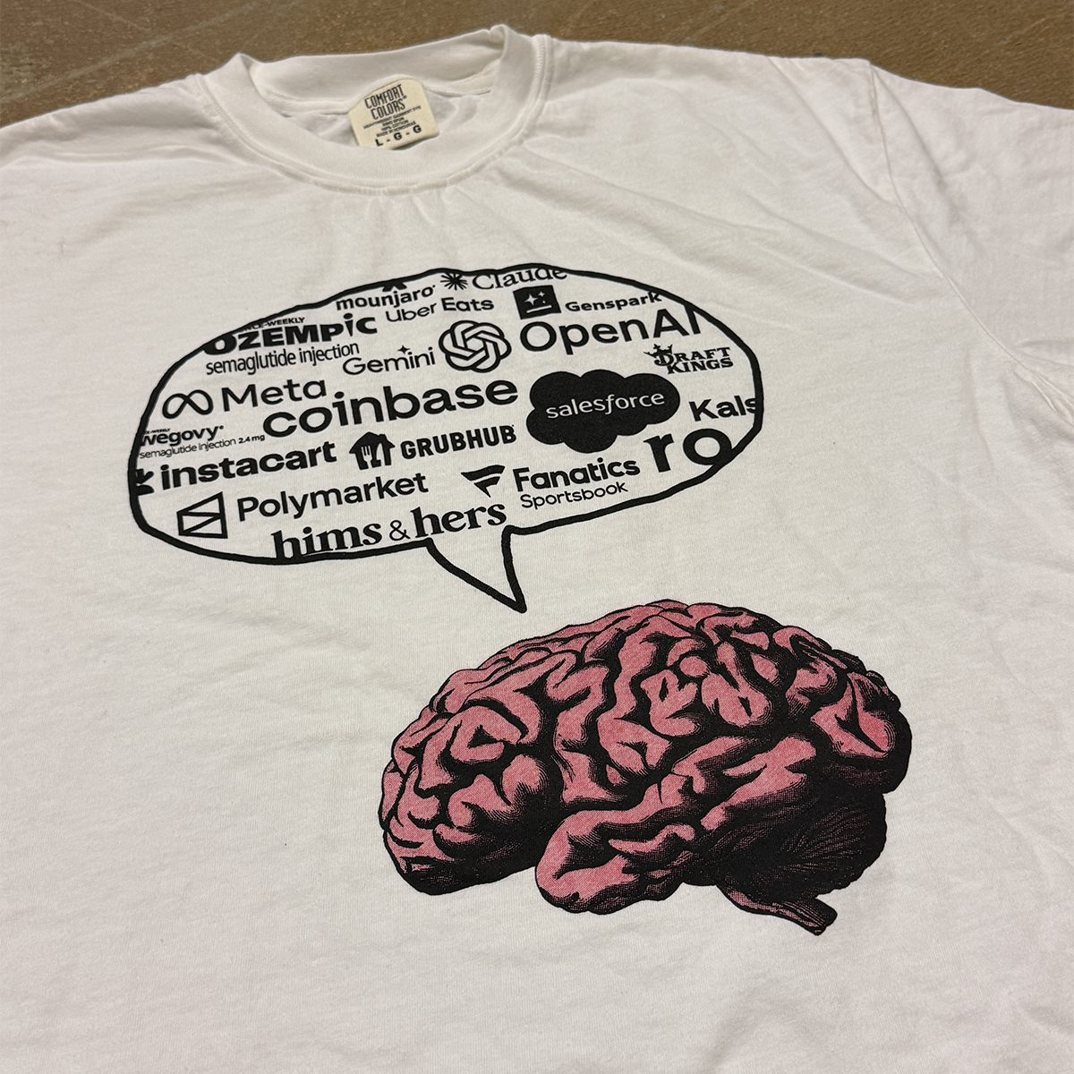 White t-shirt with a brain graphic and text bubble on a brown surface