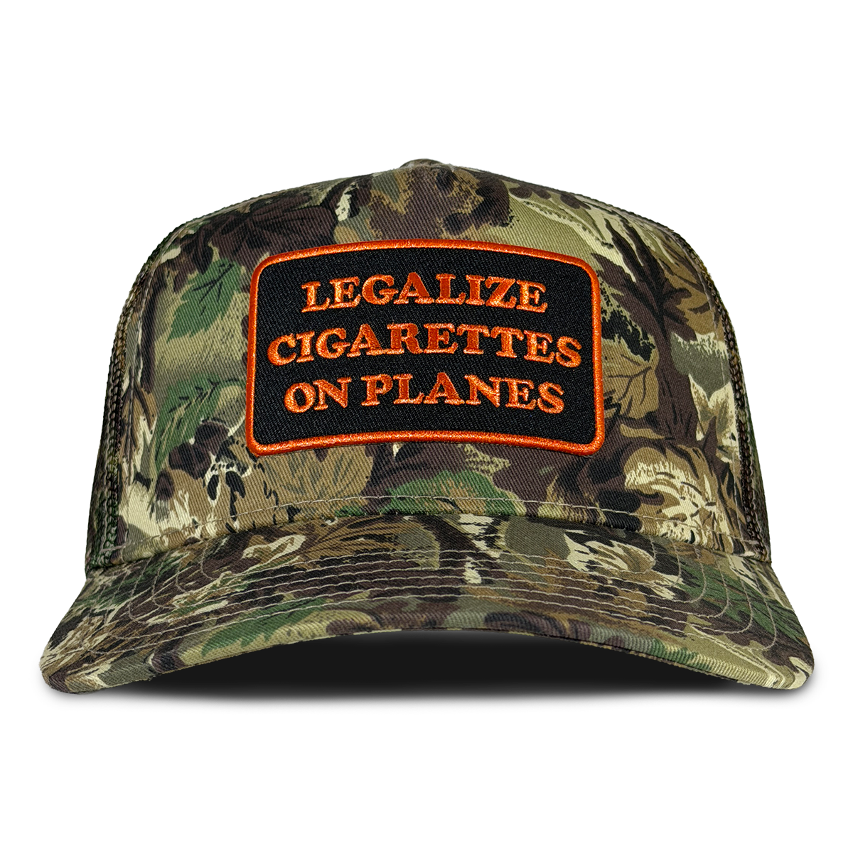 A camouflage trucker-style cap with a front patch reading 'LEGALIZE CIGARETTES ON PLANES' in orange text on a black background, shown against a plain white background. Hat by Crying in the Club Shirts