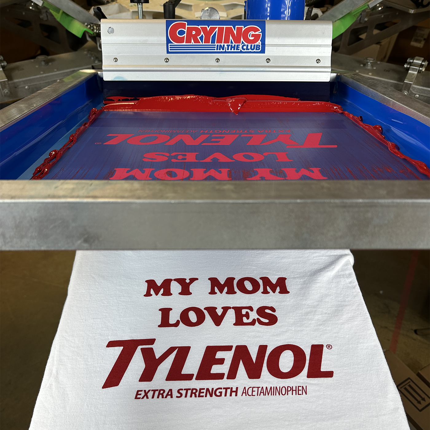 T-shirt with 'My Mom Loves Tylenol' printed on it, next to a screen printing machine. Crying in the club funny t shirts