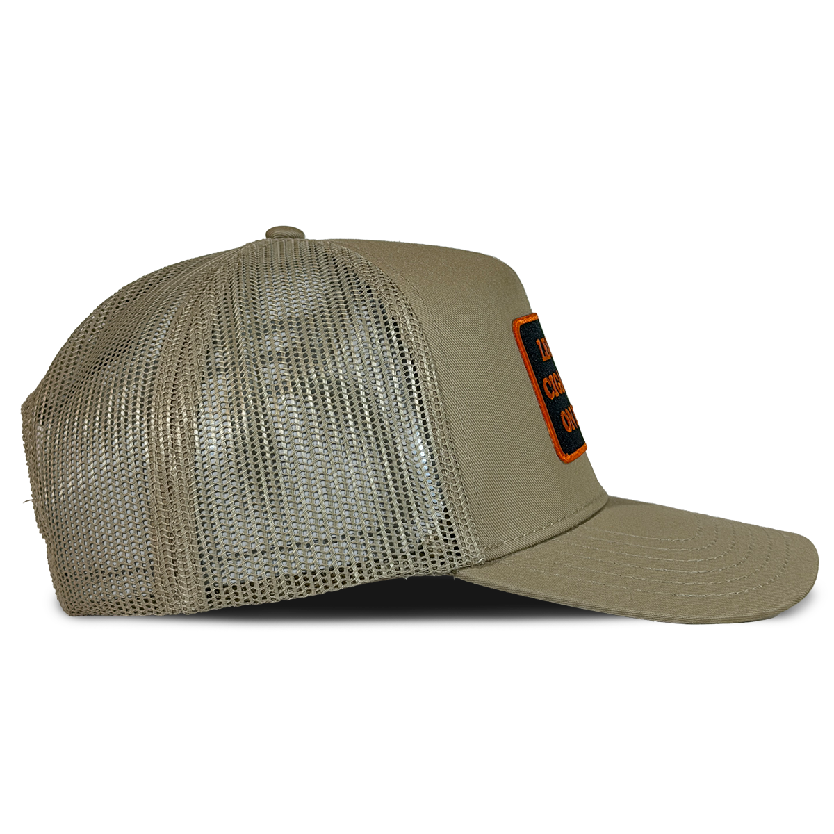 A khaki trucker hat with a mesh back and a small orange and black embroidered patch on the front right, shown against a plain white background. Hat by Crying in the Club Shirts