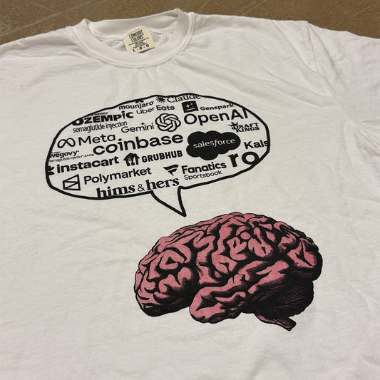 White t-shirt with a brain graphic and text bubble on a brown surface