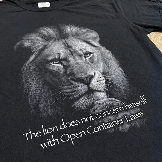Black t-shirt with a lion graphic and text on a plain background, "the lion does not concern himself with open container laws" shirt by crying in the club shirts